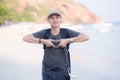 Smiling man doing heart shape with his hands the beach. Royalty Free Stock Photo