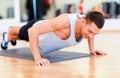 Smiling man doing push-ups in the gym