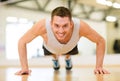 Smiling man doing push-ups in the gym