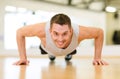 Smiling man doing push-ups in the gym