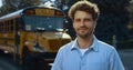 Smiling man driver posing near bus close up. Schoolbus operator looking camera. Royalty Free Stock Photo