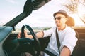 Smiling Man driving cabriolet car by province mountain road inside car view