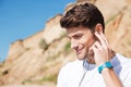 Smiling man in earphones listening to music on the beach Royalty Free Stock Photo