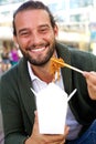 Smiling man eating take out food with chopsticks Royalty Free Stock Photo