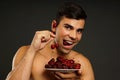 Smiling man eats red fresh cherry