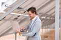 A smiling man checks the work of solar panels through a laptop. Outdoors