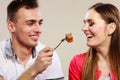 Smiling man feeding happy woman with cake.