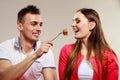 Smiling man feeding happy woman with cake.