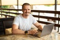 Smiling man freelancer looking in camera and working on laptop. Royalty Free Stock Photo