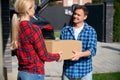 Smiling man giving box to woman standing near house Royalty Free Stock Photo