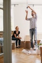 Smiling man hanging lamp while furnishing new home after moving in with his happy wife Royalty Free Stock Photo