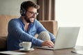 Smiling man with headphones using laptop in his home Royalty Free Stock Photo