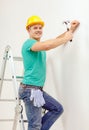 Smiling man in helmet hammering nail in wall Royalty Free Stock Photo