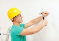 Smiling man in helmet hammering nail in wall Royalty Free Stock Photo