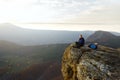 Smiling man hiker with backpack siting and relaxing on the top of the mountain and looking at beautiful yellow autumn Royalty Free Stock Photo