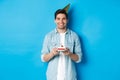 Smiling Man Holding B-day Cake And Wearing Birthday Party Hat, Celebrating Over Blue Background
