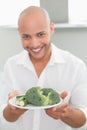 Smiling man holding a plate of broccoli