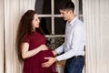 Smiling man holding pregnant belly his woman. Royalty Free Stock Photo