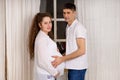 Smiling man holding pregnant woman for her belly. Young parents expecting baby Royalty Free Stock Photo