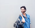 Smiling man holding travel bag and looking over shoulder Royalty Free Stock Photo