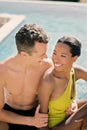 Smiling man hugging happy woman by the waist while looking at her while sitting by the pool Royalty Free Stock Photo