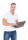 Smiling man in jeans using a laptop computer Royalty Free Stock Photo