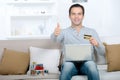 Smiling man with laptop and credit card showing thumbs up Royalty Free Stock Photo