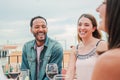 Smiling man laughing with two women friends celebrating a lunch party with wine glasses, sitting at table in the Royalty Free Stock Photo