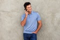 Smiling man leaning against wall and talking on mobile phone Royalty Free Stock Photo