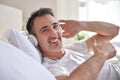 Smiling man listening music lying in bed ok sign