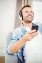 Smiling man listening to music while holding mobile phone Royalty Free Stock Photo