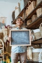 smiling man looking at the camera and holding a blackboard in a handicraft workshop