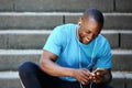 Smiling man looking at mobile phone and listening to music Royalty Free Stock Photo