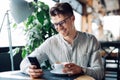 Smiling man looking at smartphone screen while resting at cafe