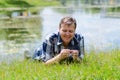 Smiling man is lying on grass on bank of pond Royalty Free Stock Photo