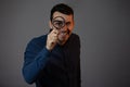 Smiling man with magnifying glass on grey background. Curious young man with magnifying glass Isolated on grey background