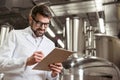 Smiling man making notes at beer factory