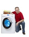 Smiling man near the washing machine and a stack of bright linen, isolated on white background Royalty Free Stock Photo