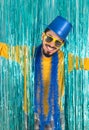 Smiling man with open arms. Brazilian wears a top hat, sunglasses, and a yellow t-shirt. Bright curtain. Concept of new year