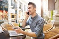 Smiling man on phone call at outside cafe with laptop Royalty Free Stock Photo