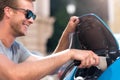 Smiling man plugging cable to electric car