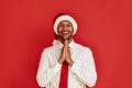 Smiling Man Prayer Gesture. Handsome Multiracial Man Wearing Santa Hat Praying