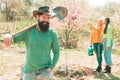 Smiling man preparing to planting. Man plants a tree. Friends working in garden. Group of youth work in spring yard with Royalty Free Stock Photo