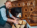 Smiling man putting wood logs in the home mantel fire.Home sweet home and winter countryside holidays concept image Royalty Free Stock Photo