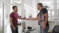 Smiling man receives car keys in dealership, satisfied customer handshake with salesperson in showroom office, vehicle