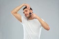 Smiling man shaving beard with trimmer over gray