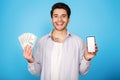 Smiling man showing blank phone screen, holding bunch of money Royalty Free Stock Photo