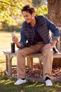 Smiling Man Sitting On Bench In Autumn Park Using Mobile Phone Royalty Free Stock Photo