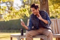 Smiling Man Sitting On Bench Making Video Call In Autumn Park Using Mobile Phone Royalty Free Stock Photo