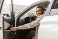 Smiling man sitting in the car, getting in or out of the car, holding the door open, looking at the camera Royalty Free Stock Photo